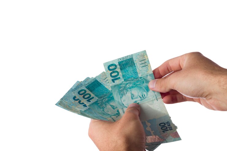 Foto hombre que sostiene billetes de cien reales aislados en blanco. dinero brasileño.