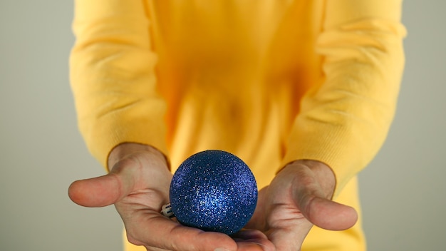 Un hombre que sostiene una bola de Navidad azul en la mano. Foto de alta calidad