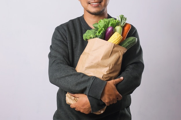 Hombre que sostiene la bolsa de compras con verduras para el concepto de estilo de vida saludable