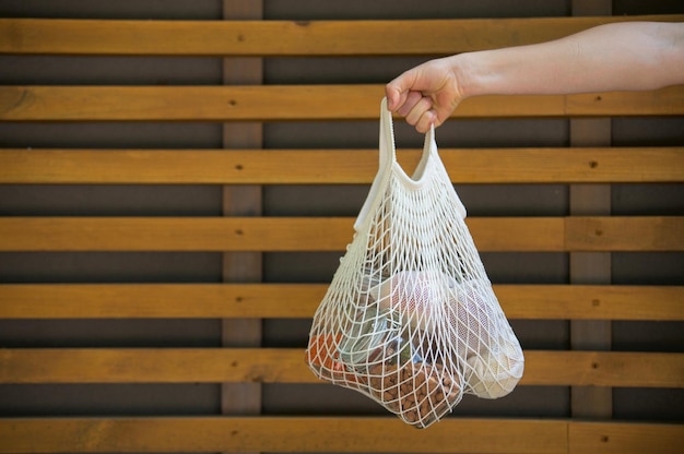 hombre que sostiene una bolsa de malla con productos sin envases de plástico