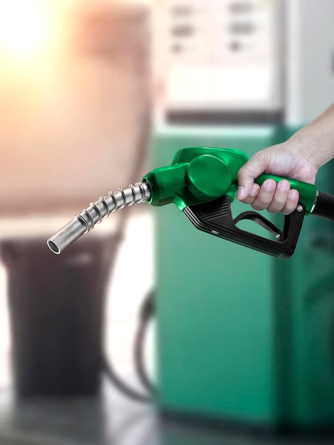 Hombre que sostiene la boquilla de combustible en la gasolinera