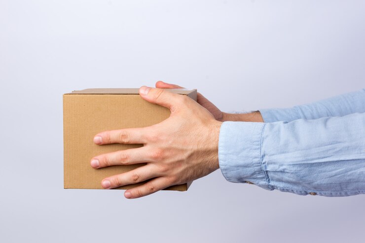 Foto hombre que sostiene la caja de cartón cuadrada con el brazo extendido. entrega de paquetes. vista lateral.