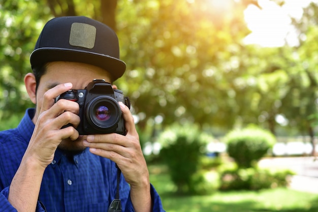 Hombre que sostiene la cámara DSLR y toma foto