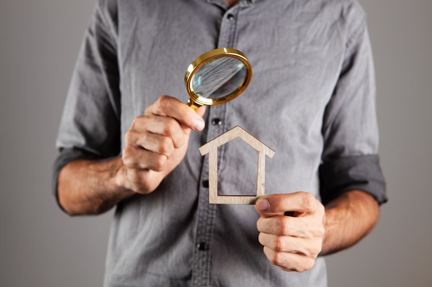 Foto hombre que sostiene una casa y una lupa. concepto de búsqueda de inicio