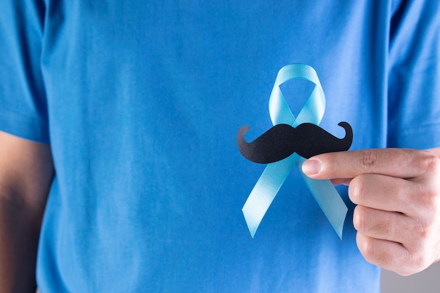 Hombre que sostiene la cinta azul claro con bigote.