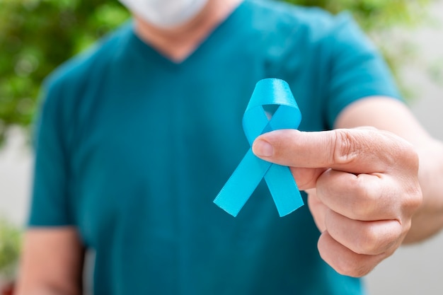 Foto hombre que sostiene la cinta azul. noviembre azul. mes de la prevención del cáncer de próstata. salud de los hombres.