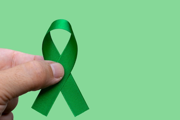 Hombre que sostiene una cinta verde. concepto de mes de concientización sobre el cáncer de hígado, vesícula biliar, riñón y linfoma.