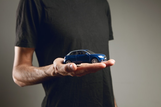 Un hombre que sostiene un coche de juguete en sus manos.