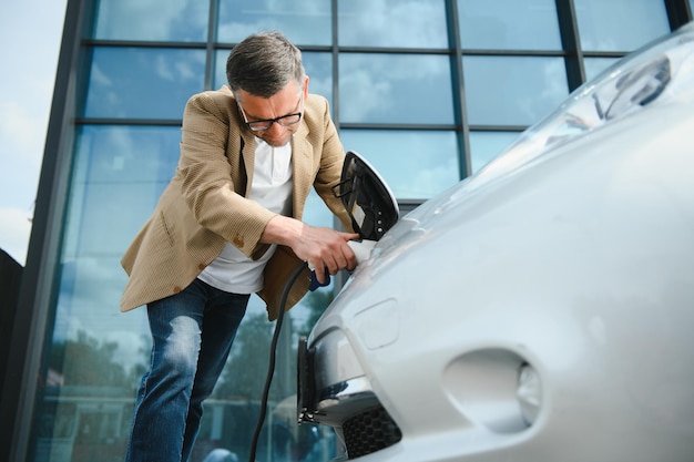 Hombre que sostiene el conector de alimentación para coche eléctrico