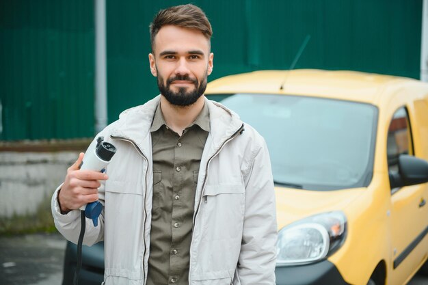 Hombre que sostiene el conector de alimentación para coche eléctrico