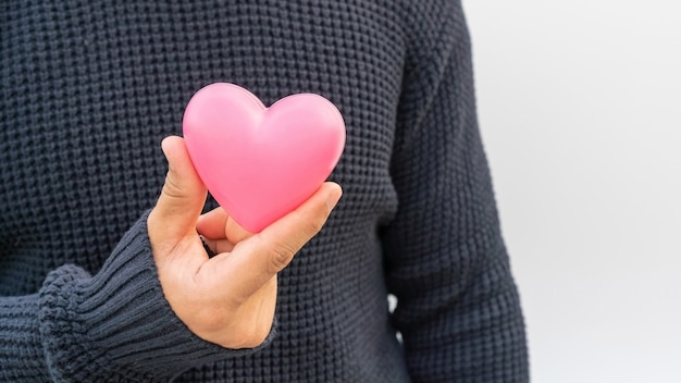 Hombre que sostiene un corazón rosado en blanco