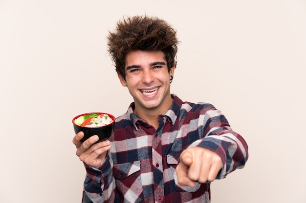 El hombre que sostiene un cuenco lleno de fideos te señala con una expresión segura