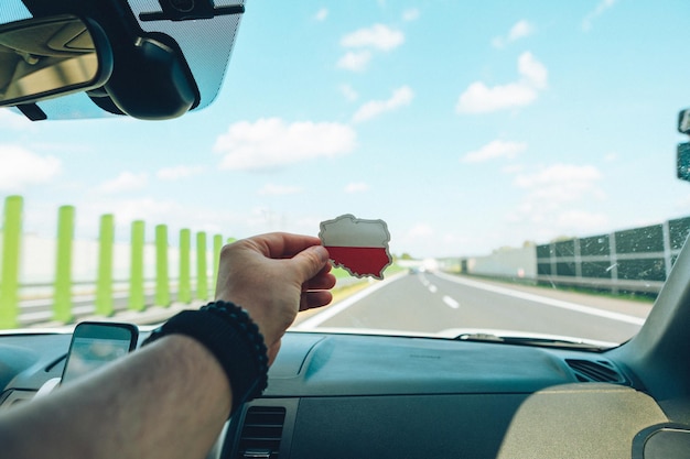 Hombre que sostiene la etiqueta engomada con la bandera de polonia frente a la carretera