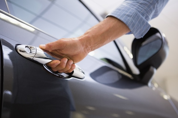 Hombre que sostiene las manijas de las puertas de un coche