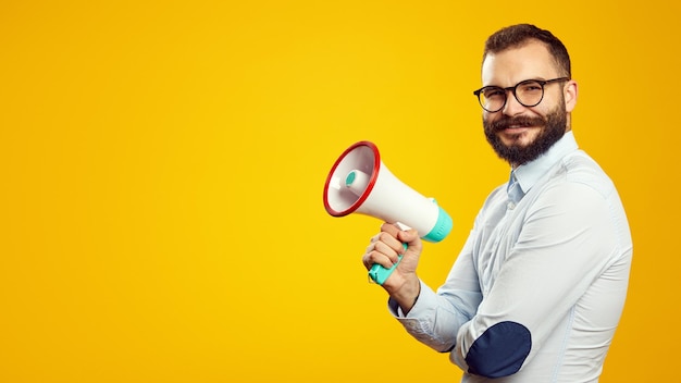 Hombre que sostiene el megáfono y sonriendo mientras está de pie aislado sobre amarillo