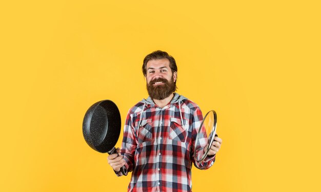 Hombre que sostiene la sartén chef masculino cocina hipster camisa a cuadros para chico barbudo cocinero hombre brutal sin afeitar con utensilio de cocina artículos para el hogar asistente de tienda amigable