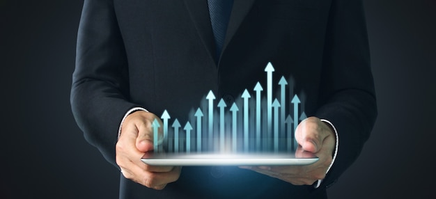 Hombre que sostiene una tableta con un gráfico de crecimiento y aumento de indicadores positivos en una empresa