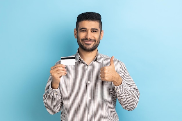 El hombre que sostiene la tarjeta de crédito recomienda descuentos bancarios o de compras que muestran el pulgar hacia arriba