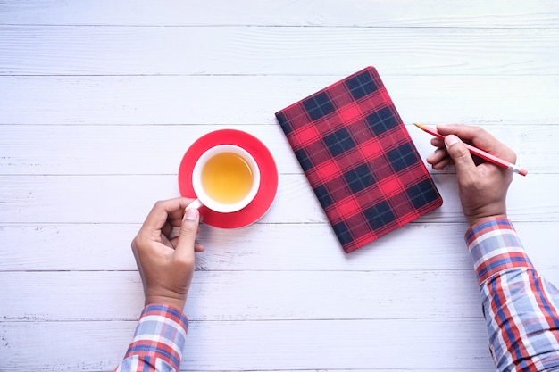 Hombre que sostiene la taza de té caliente en la mesa.