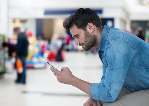 Hombre que sostiene el teléfono en el centro comercial mall