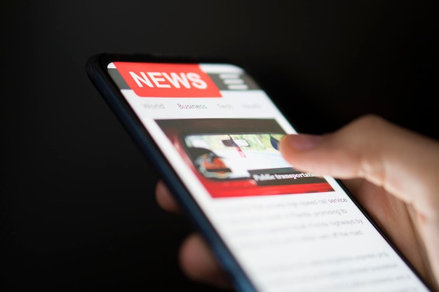 Foto un hombre que sostiene un teléfono inteligente móvil con noticias en la pantalla portal en línea del periódico en el navegador