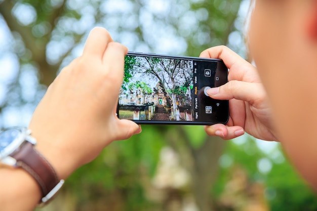 Un hombre que toma la foto con el teléfono celular móvil. Tomar fotos por teléfono inteligente en el antiguo templo de vuelta