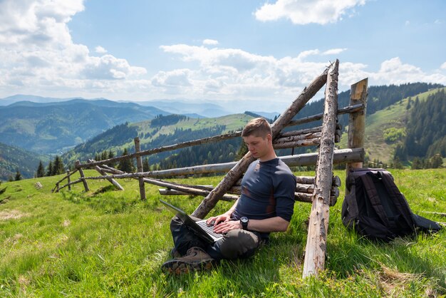 Hombre que trabaja en la computadora portátil al aire libre en la naturaleza