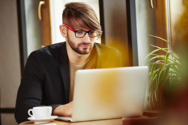 Hombre que trabaja en la computadora portátil en café