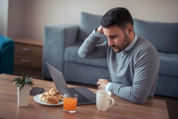 Hombre que trabaja en la computadora portátil en casa