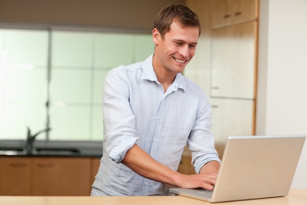 Hombre que trabaja en la computadora portátil en la cocina