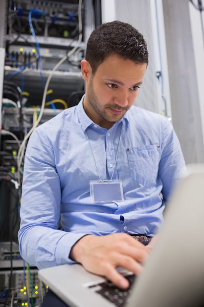 Foto hombre que trabaja en la computadora portátil delante de los servidores