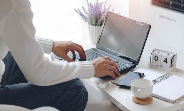 Hombre que trabaja con la computadora portátil mientras está sentado en la sala de estar en casa, trabajando desde casa concepto.