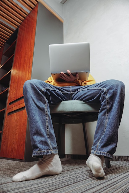 El hombre que trabaja en la computadora portátil se sienta en la silla. Hombre hacker escribiendo en la computadora portátil, pirateando el sistema informático.