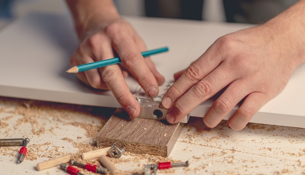 Hombre que trabaja con un destornillador eléctrico durante el proceso de fabricación de muebles de madera