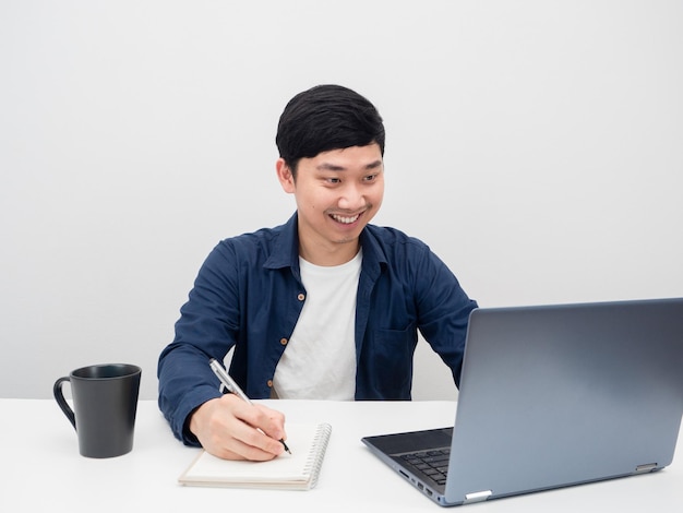 Hombre que trabaja en el escritorio con una computadora portátil con un fondo blanco sonriente