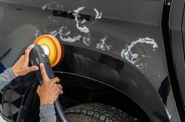 Hombre que trabaja para pulir, revestir coches. el pulido del automóvil ayudará a eliminar los contaminantes en la superficie del automóvil