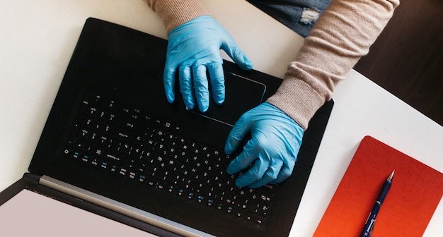 Un hombre que trabaja desde su casa en una computadora portátil con guantes desechables para protección. Brote de coronavirus. Hombre de negocios en cuarentena. Trabajar en casa. Quédate en casa.