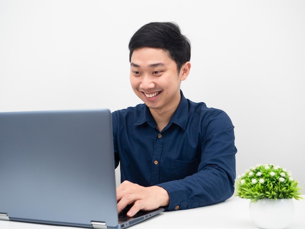 El hombre que trabaja con su computadora portátil se siente feliz y sonríe en el concepto de trabajo de mesa desde casa