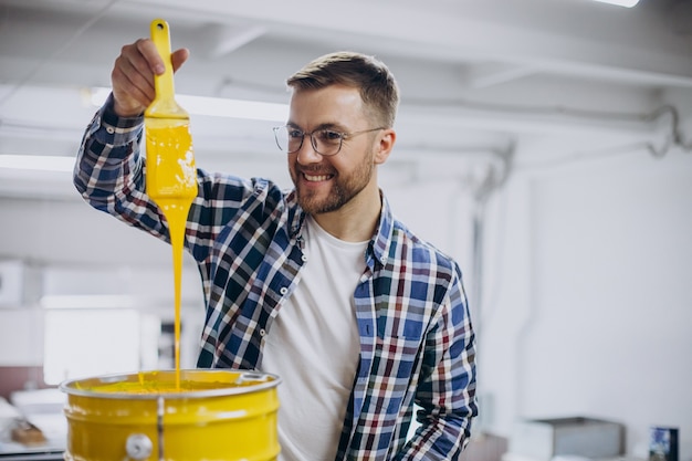 Hombre que trabajaba en la imprenta con papel y pinturas