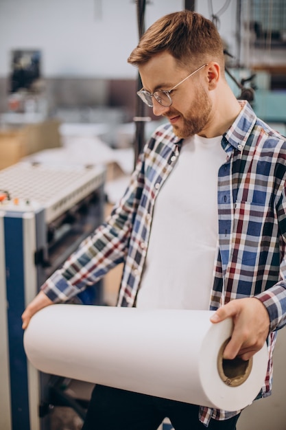 Hombre que trabajaba en la imprenta con papel y pinturas