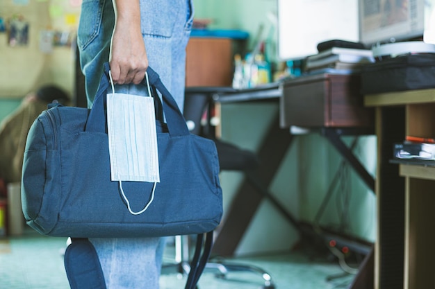 Foto hombre que va a trabajar con bolsa para portátil y máscara protectora en mano hombre con maletín y desechables