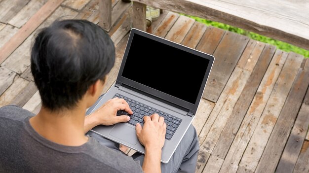 Hombre que usa una computadora portátil en el balcón