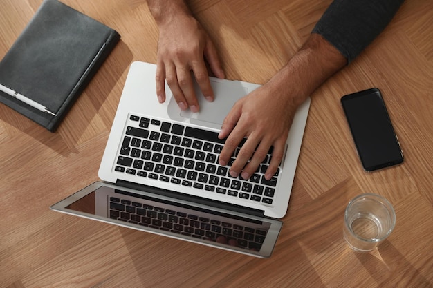 Hombre que usa la computadora portátil para buscar en la vista superior de la mesa de madera