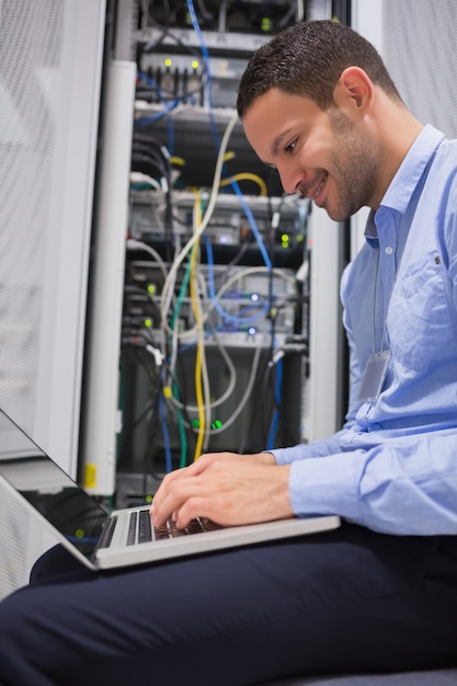 Foto hombre que usa la computadora portátil delante de los servidores