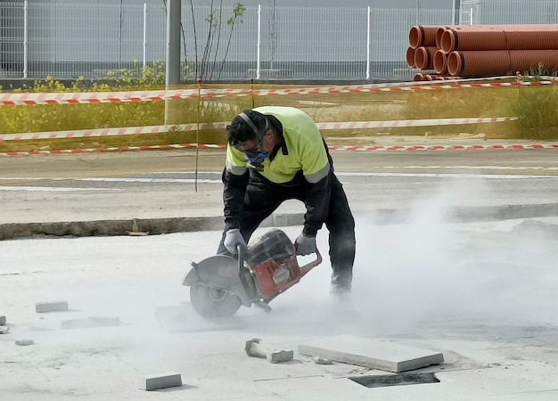 Un hombre que usa un piso de concreto de corte con una máquina de hoja de sierra de diamante