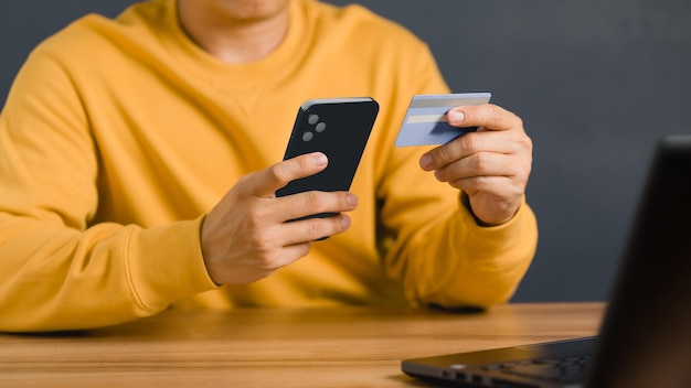 Foto un hombre que usa tarjeta de crédito para comprar y comprar en línea en el teléfono móvil.