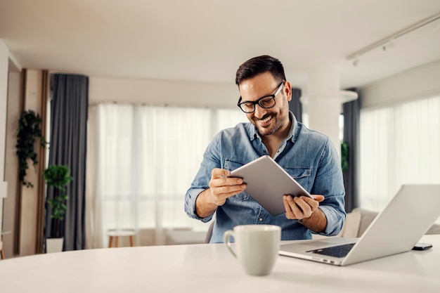 Un hombre que usa tecnologías y sostiene una tableta mientras está sentado en casa