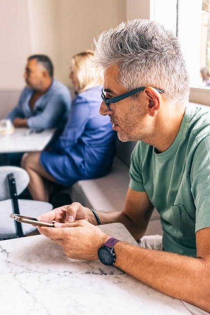 Foto hombre que usa el teléfono celular para consultar el menú del restaurante antes de ordenar