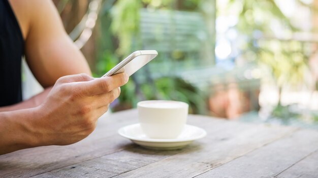 Hombre que usa un teléfono inteligente en una cafetería.