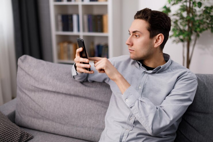 Hombre que usa el teléfono inteligente en el sofá